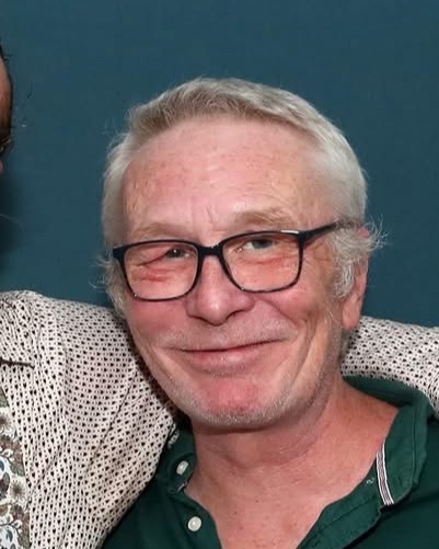 Andrew, smiling, in a green polo shirt and glasses
