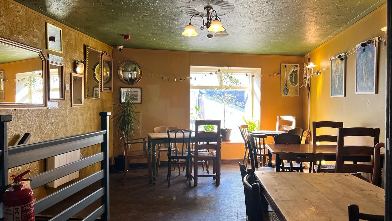 The Cwtch, the room upstairs at the Warren: mustard walls, old mirrors and wooden tables in afternoon sun