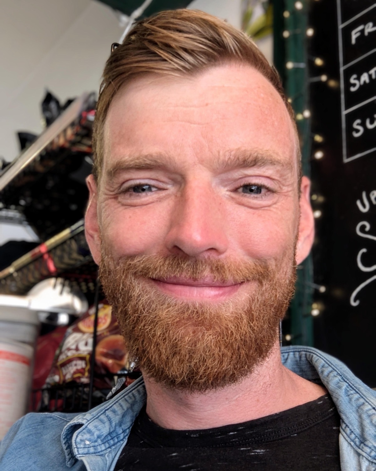 Pete, smiling, with a red beard, in a denim shirt