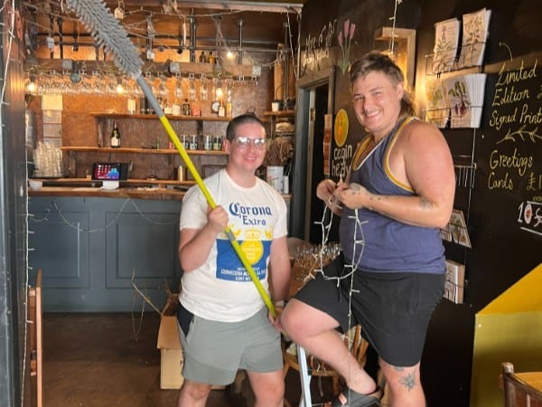 Two volunteers hanging fairy lights at The Warren on a Thursday morning