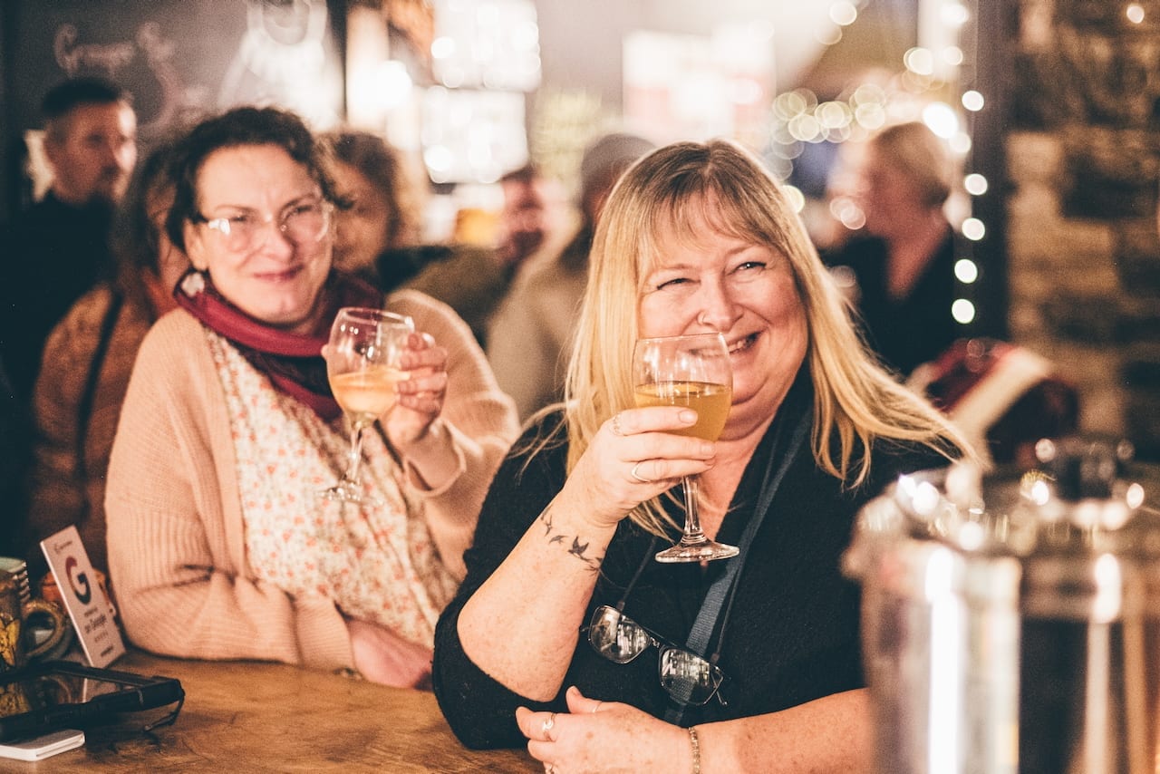 Two guests at the bar at the Warren, one raising a glass of white wine