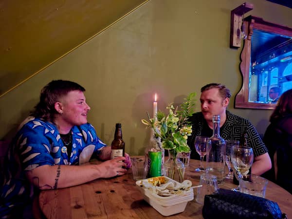 Two people at a candlelit table with wine glasses and a bottle