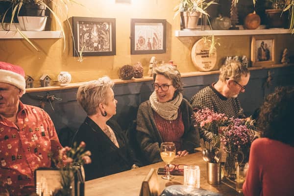 Guests round a table with glasses of wine and flowers