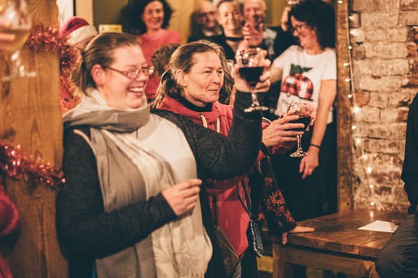 A group of women laughing and raising glasses of wine