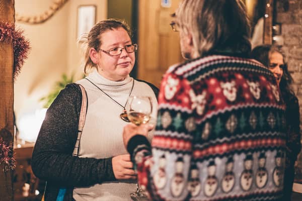 A woman holding a glass of white wine, chatting at a party