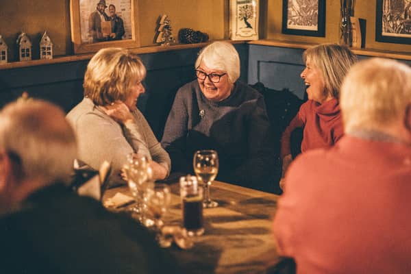 Friends talking round a wooden table with glasses of wine