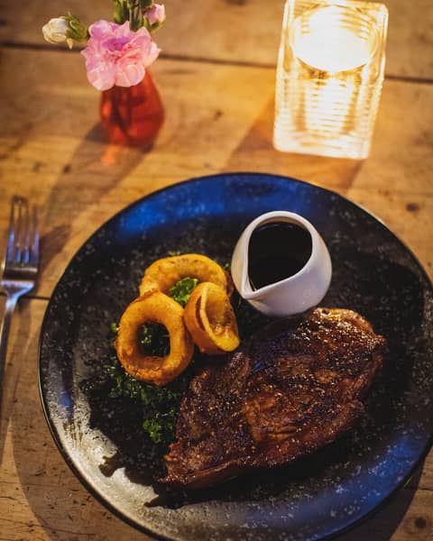Steak with onion rings and a jug of gravy