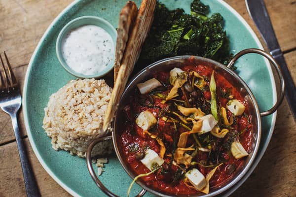 A pan of stew with rice, flatbread and greens
